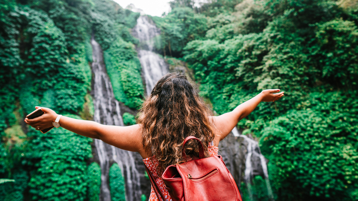 Anonymous female traveler admiring amazing waterfall